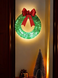 Festive Christmas wreath with red bow and LED lights hanging on a warm beige wall