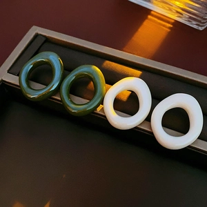 Close-up of four resin oval rings in dark green and white finishes inside a jewelry box