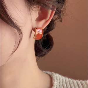 Retro golden square stud earrings with orange resin inlay worn by a model