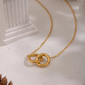 Gold interlocking circle necklace on white stone with elegant pine cone decoration