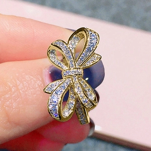 Détail macro d'une bague nœud dorée avec design double couche et zircons scintillants