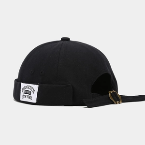 Detail of adjustable black docker cap strap with vintage gold metal buckle closure