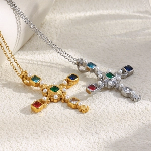 Close-up of gold and silver cross necklaces with colorful gemstones and pearls