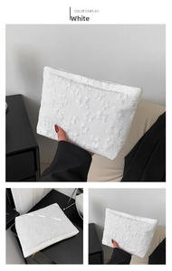 Detail of white embossed floral jacquard fabric with gold zipper on a slim clutch bag
