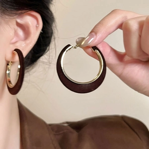 Detail of vintage deep brown velvet texture and golden metal hoop earrings on model