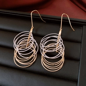 Detail of mixed-metal multi-layer circular hoop earrings on elegant silk and leather background