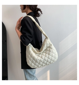 Detailed side view of a white quilted tote bag featuring a puffer texture and soft strap