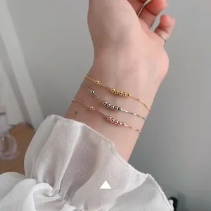 Detailed close-up of three minimalist bead bracelets in gold, silver, and rose gold