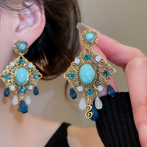 Detail of vintage gold-toned dangle earrings featuring hollow filigree and turquoise stones