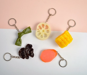 Macro shot of realistic PVC food keychains including lotus root, corn, and ham slices