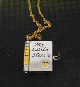 Detail of book-shaped necklace engraved with My Little Hero and a heart cutout detail