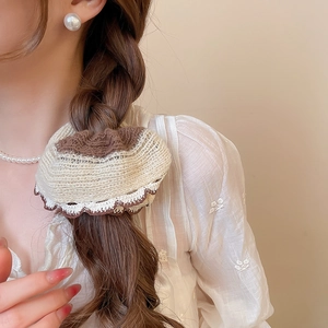 Detail of knitted lace scrunchie in coffee and beige on a low ponytail braid