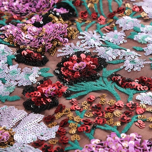 Vue macro de broderies de paillettes de luxe sur tulle avec motifs floraux colorés