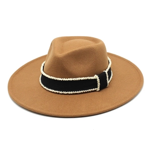 Detailed close-up of a camel wool fedora hat with black ribbon and white pearl accents