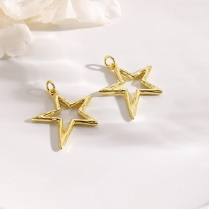 Detail of two gold hollow star charms with small rings for DIY jewelry making
