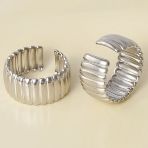 Detailed view of silver minimalist open rings with vertical striped texture on yellow background