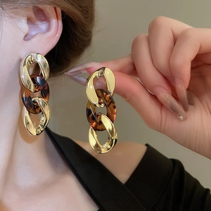 Macro detail of tortoiseshell resin and golden metal chain link drop earrings