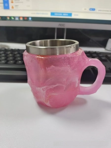 Detail of pink crystal-texture resin coffee mug with polished stainless steel rim