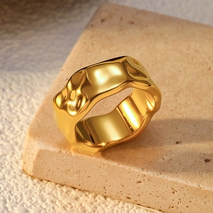 Macro detail of vintage gold ring with irregular lava texture resting on a natural beige stone