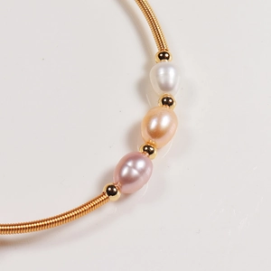 Macro view of handmade gold wire-wrapped bracelet with three multi-colored pearls