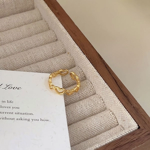 Detail of 18K gold heart chain ring on beige linen display tray with vintage card