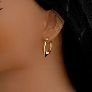 Close-up of golden twisted hoop earring on model showing polished metallic texture