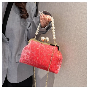 Detail of red velvet shell bag with pearl handle, gold patterns and metal chain strap