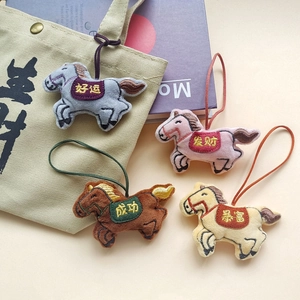 Detailed view of plush horse charms with Chinese embroidery on a canvas bag background