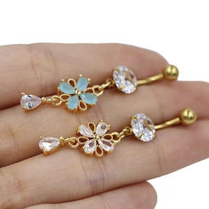 Vue macro détaillée de piercings de nombril fleur dorés avec zircons bleus et transparents