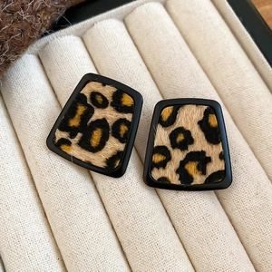Close-up of leopard print heart earrings in a beige velvet jewelry box with warm tones