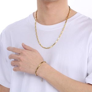 Close-up of golden geometric bamboo link chain necklace and bracelet set on male model