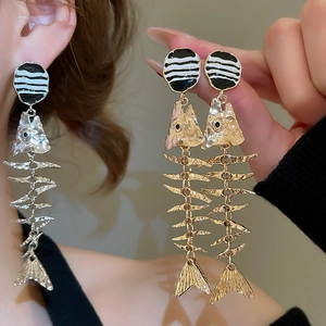 Macro detail of gold fishbone pendant earrings with black and white enamel stud detail