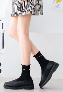 Detail of black crew socks featuring ruffled lace edges and delicate white pearl beadings