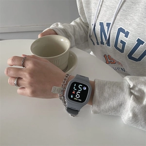 Gray rectangular smart watch with silicone strap shown on wrist with a casual lifestyle vibe