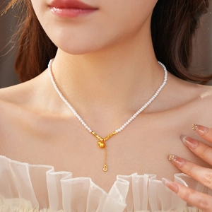 Close-up of pearl necklace with gold gourd pendant worn on a female model neck