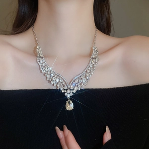 Close-up of silver V-shaped necklace with shimmering crystals and a pear-shaped pendant