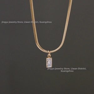 Détail de la chaîne serpent dorée avec pendentif en zircon rectangulaire clair et poli miroir