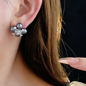 Detailed close-up of a flower stud earring with grey pearls and sparkling crystal center