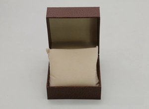 Detail view of flip-top dark brown faux leather watch box with creamy white pillow insert