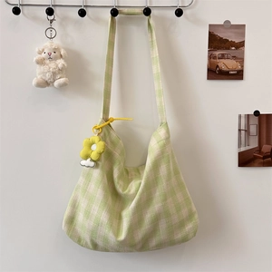 Close-up of light green checkered canvas tote bag with floral pendant and fabric texture