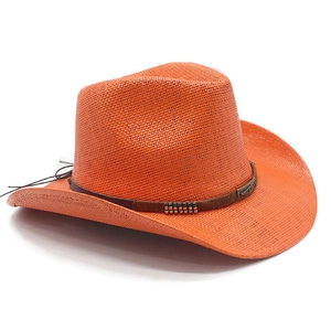 Close-up of orange straw cowboy hat featuring a brown band and vintage metal accents