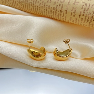 Polished 18k gold water-drop stud earrings on champagne silk background