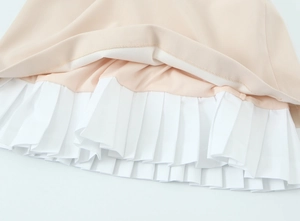Vue macro détaillée de l'ourlet plissé et des coutures en mousseline bicolore de la robe