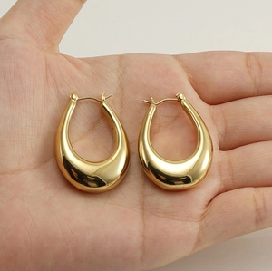 Detailed view of large gold teardrop earrings held in hand to show scale and polished finish