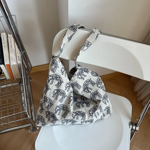 Detail of beige canvas tote bag with black leopard print resting on a white chair