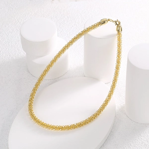 Minimalist gold braided mesh choker necklace on elegant white geometric display pedestals