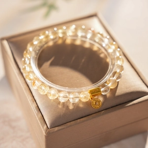 Detail of yellow rutilated quartz beaded bracelet with a gold coin charm on a jewelry box