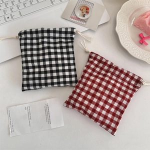 Flat lay of checkered cotton drawstring pouches in black and red on a white desk