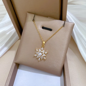 Elegant gold necklace with pearl snowflake pendant and cubic zirconia on silk base