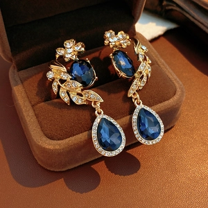 Détail macro de boucles d'oreilles vintage dorées avec pierres bleues et zircons